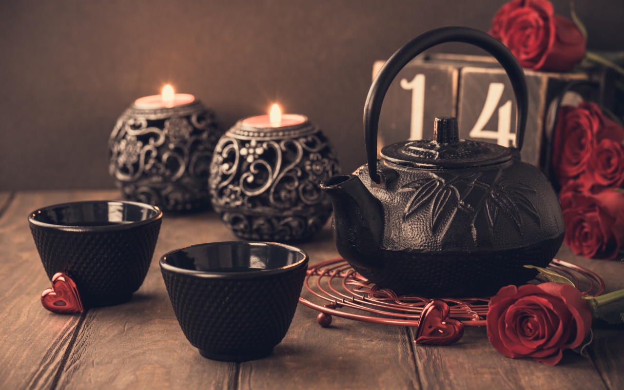 Две чашки чая на столе со свечами и красными розами
