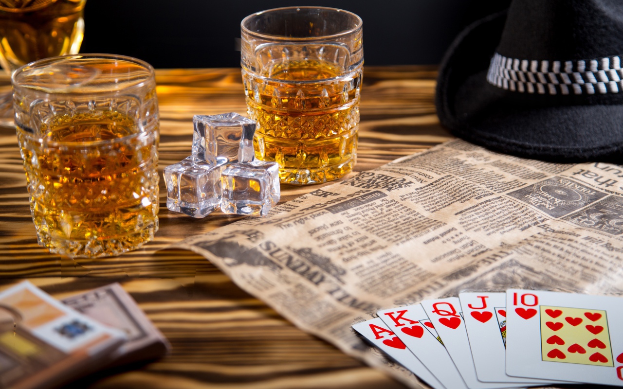 Виски со льдом на столе с картами, газетой и шляпой