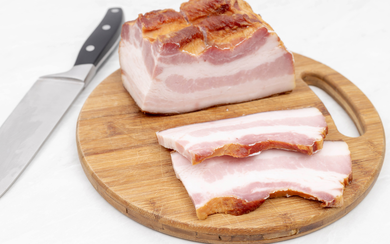 Кусок вкусного копченого сала на доске с ножом