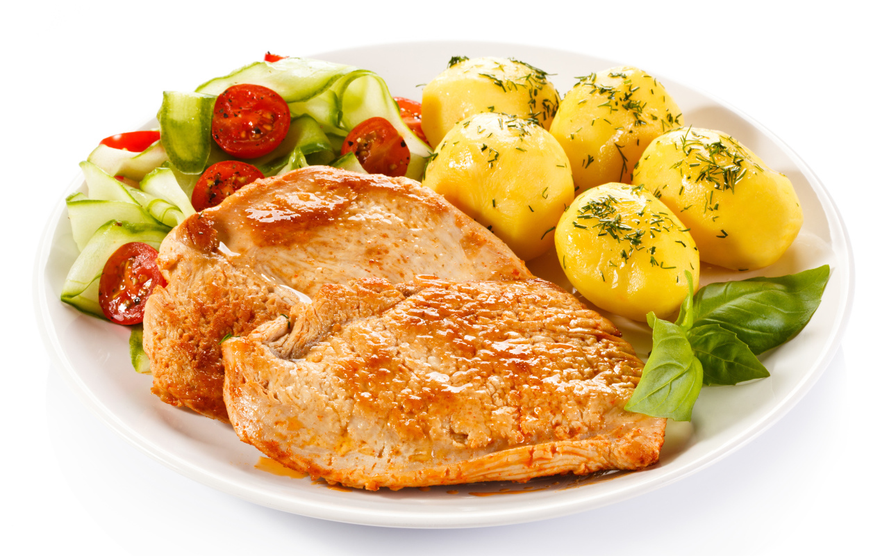 Кусок сочного куриного мяса на тарелке с картофелем и салатом