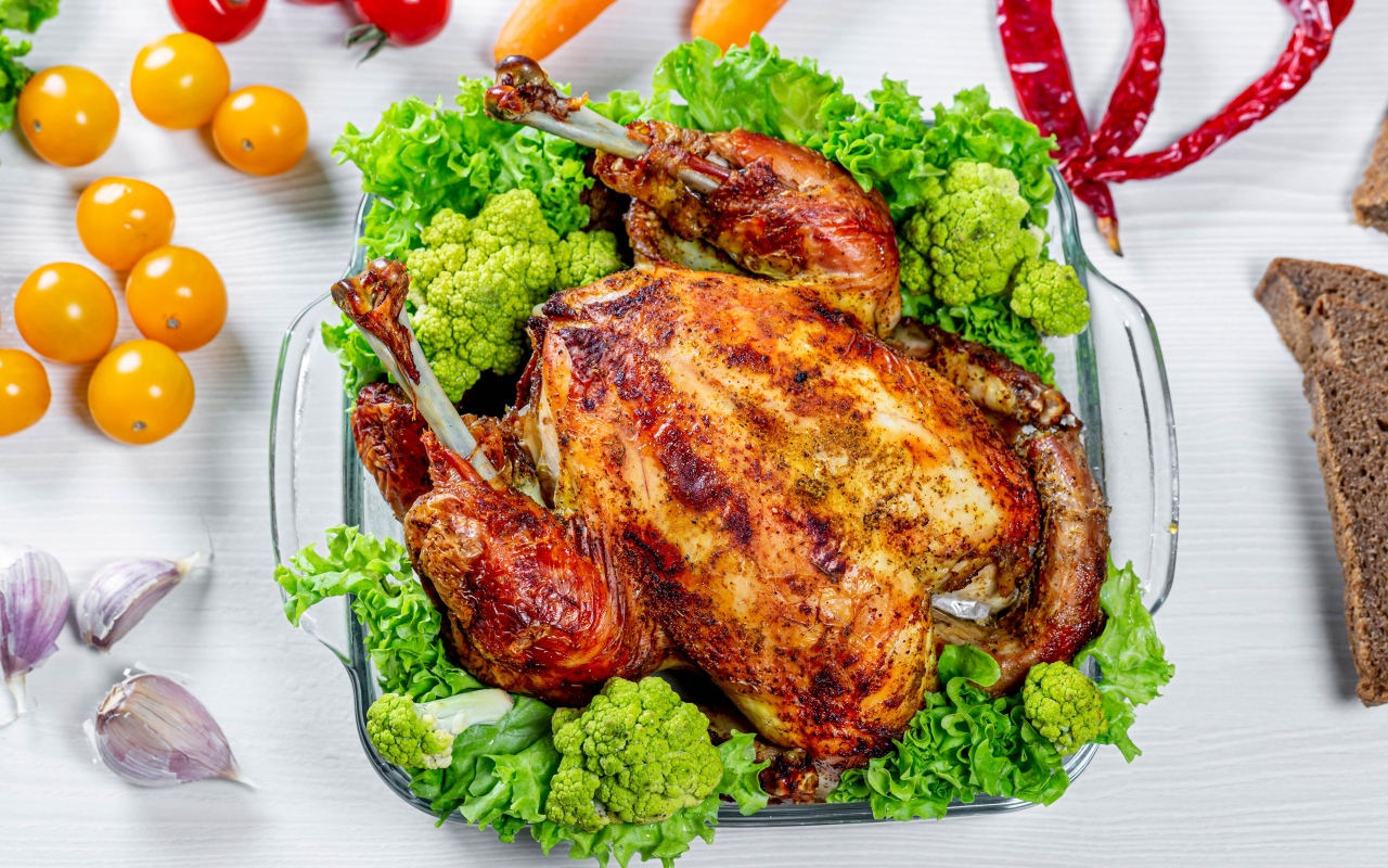 Запеченная курица с брокколи и листьями салата на столе с овощами