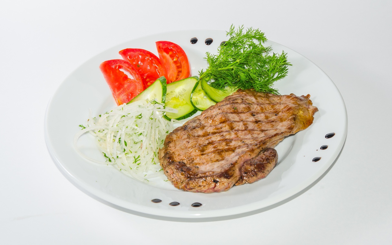 Кусок курицы с овощами на белой тарелке 