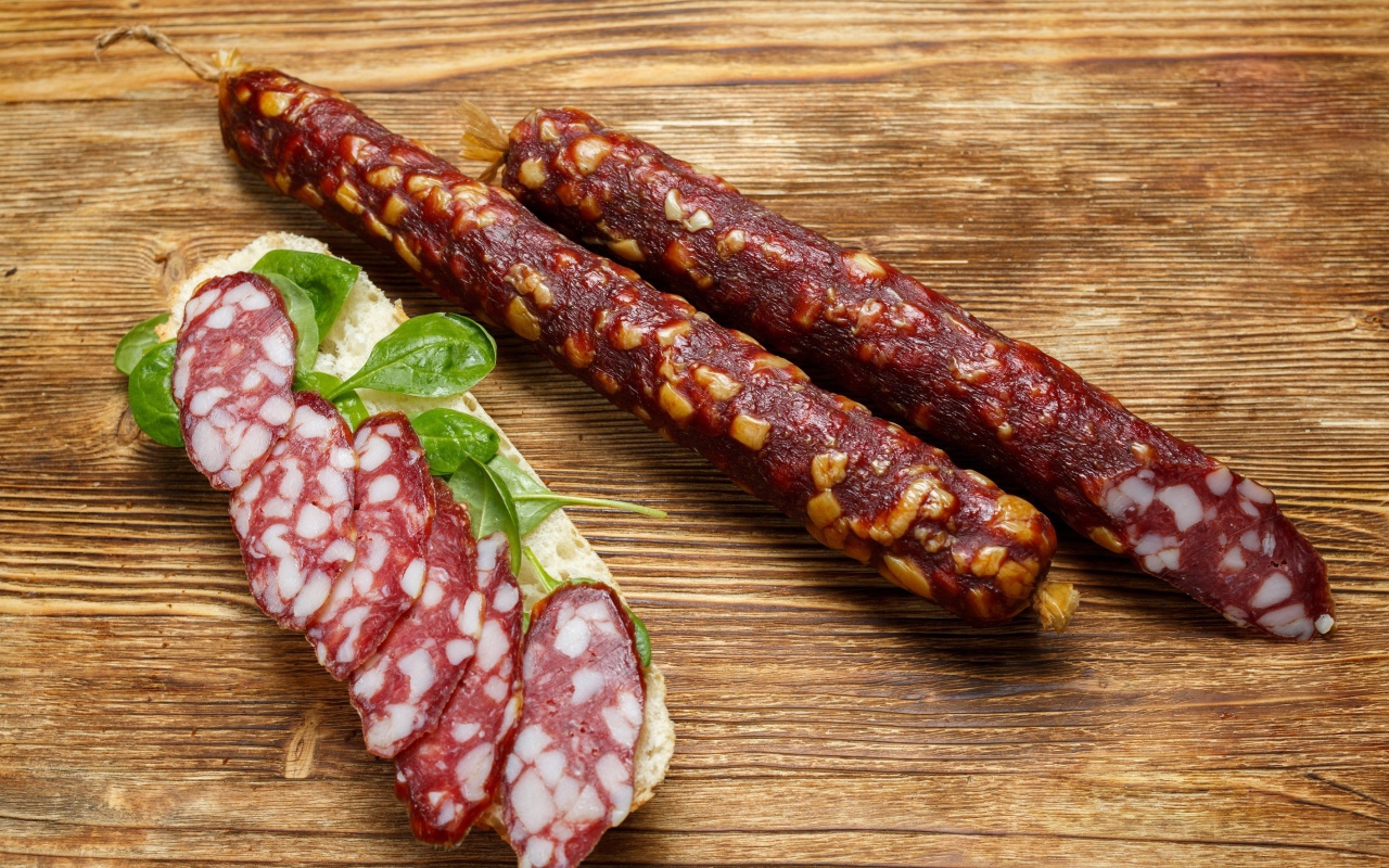 Вкусная сухая колбаса на столе с бутербродом