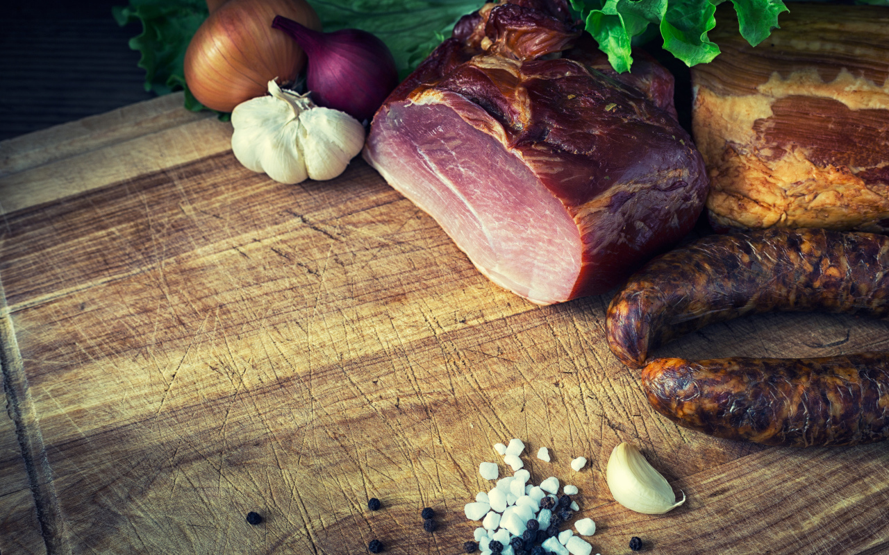 Мясные продукты на столе со специями, луком и чесноком 