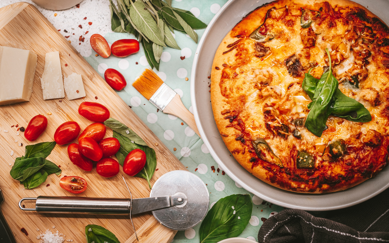 Румяная пицца на столе с сыром и помидорами