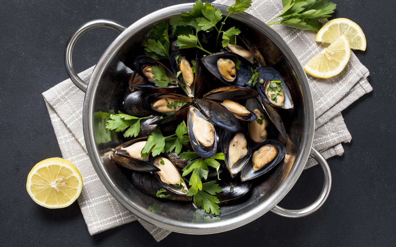 Свежие мидии в кастрюле с зеленью петрушки 