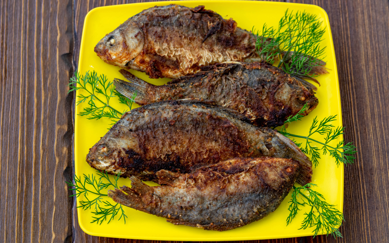 Жареные караси с укропом на желтой тарелке 