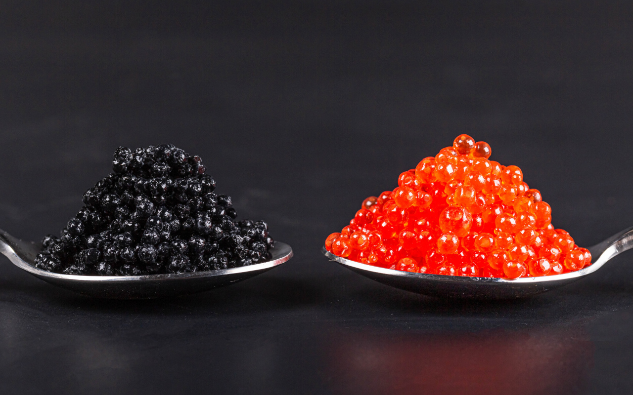 Красная и черная икра на ложках на сером фоне