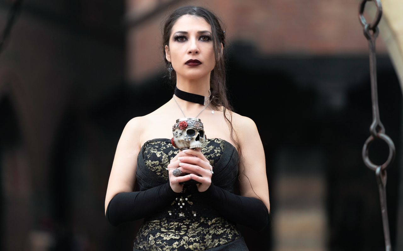 Девушка готка с бокалом - черепом в руках 