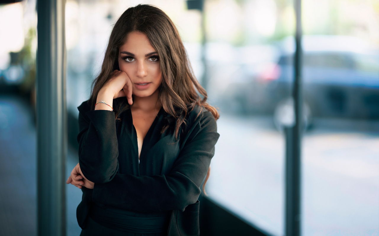 Милая девушка в черном наряде стоит на остановке