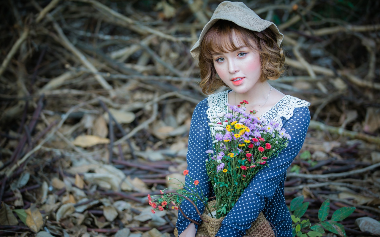 Молодая девушка азиатка с букетом цветов сидит на ветках