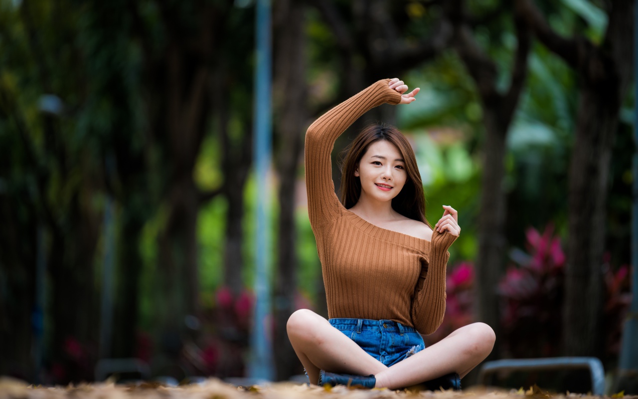 Девушка азиатка сидит в позе лотоса в парке 