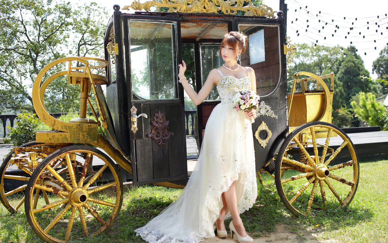 Красивая девушка азиатка в свадебном платье у кареты 