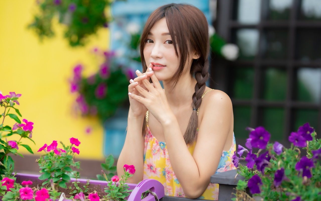 Красивая девушка Азиатка у цветов петунии