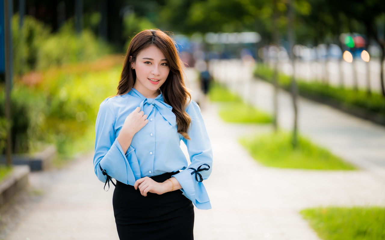 Красивая азиатка в голубой блузке и черной юбке 