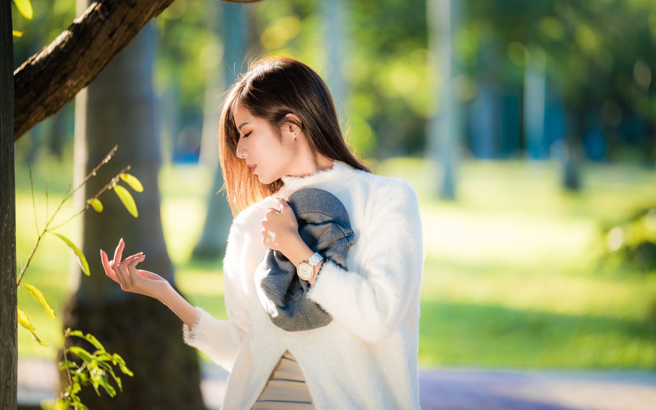 Красивая азиатка в белой кофте в солнечном парке