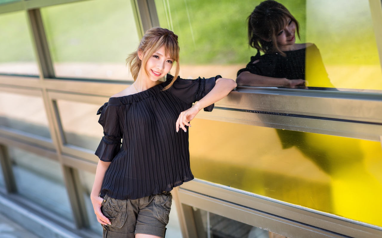 Красивая девушка азиатка в черной блузке у окна