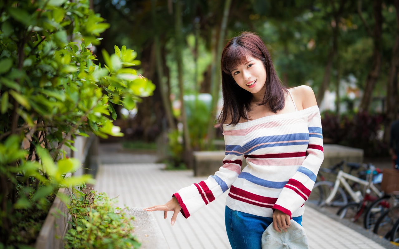 Красивая азиатка в полосатом свитере в парке