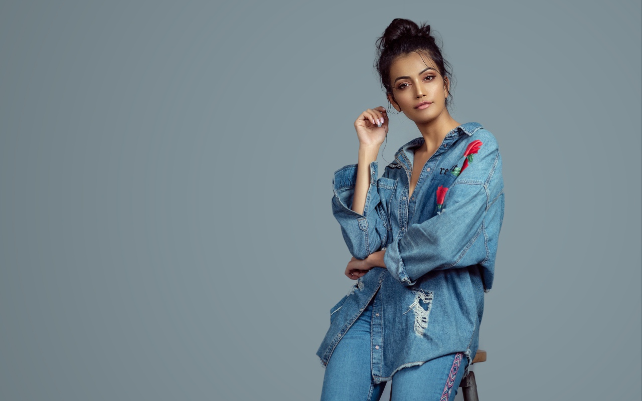 Красивая девушка в джинсовом костюме на сером фоне