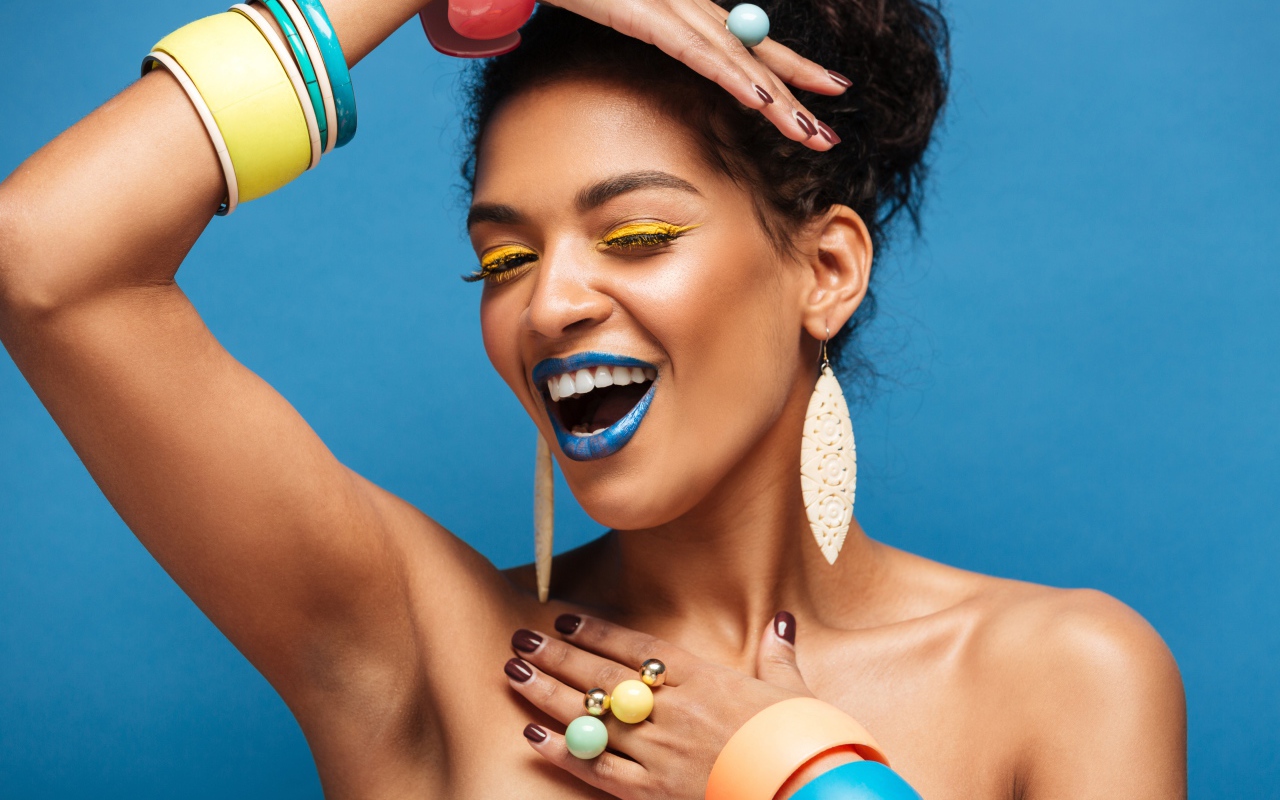 Красивая молодая девушка с ярким разноцветным макияжем на голубом фоне