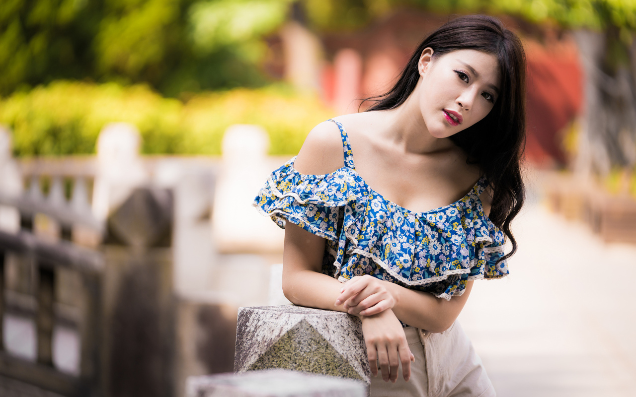 Кареглазая азиатка в яркой кофте в парке 