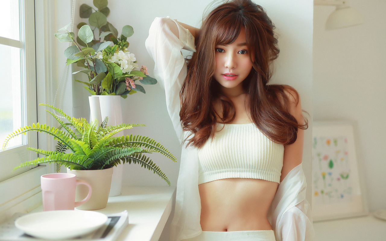 Нежная девушка азиатка стоит у окна