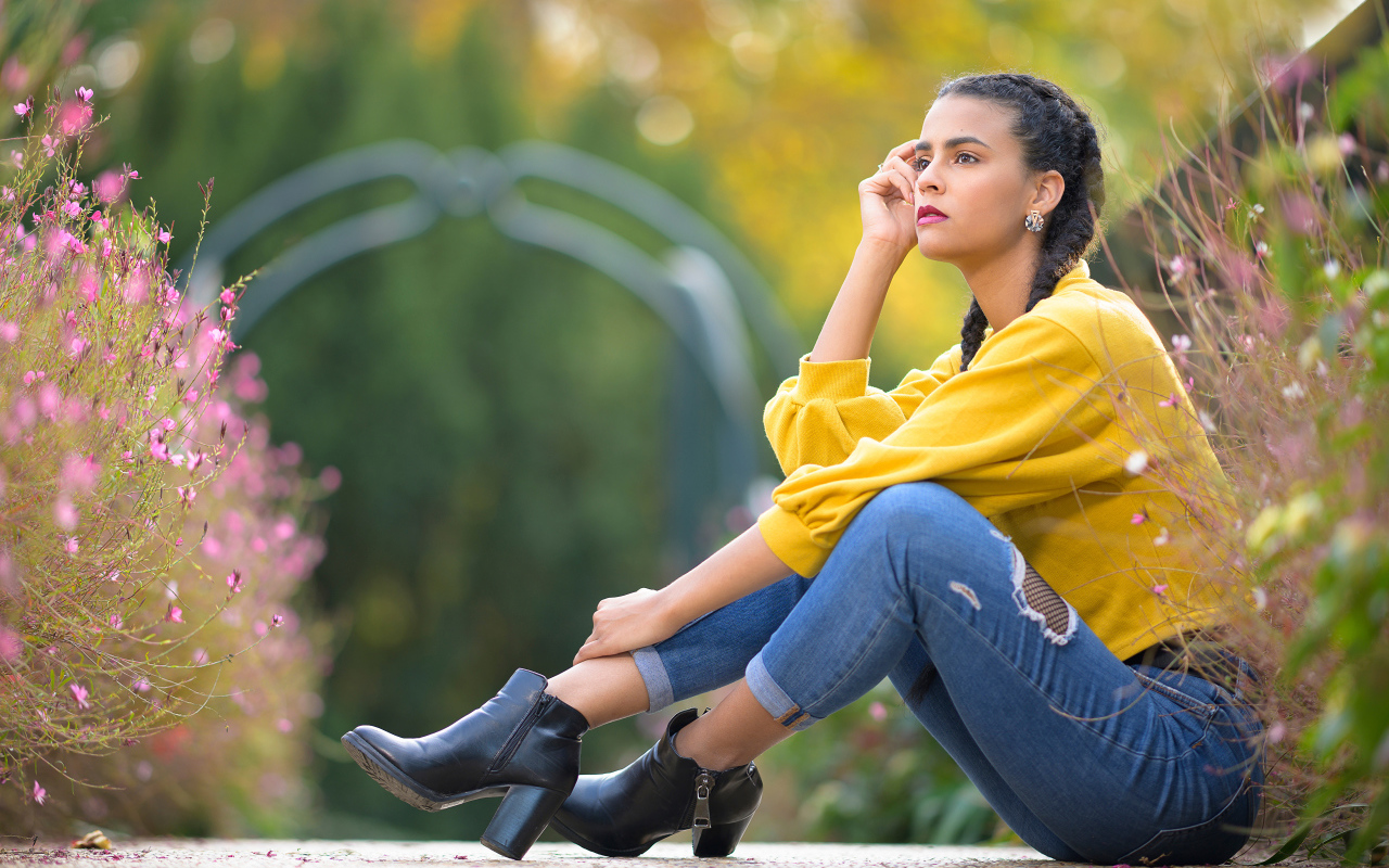 Девушка в джинсах сидит на земле 