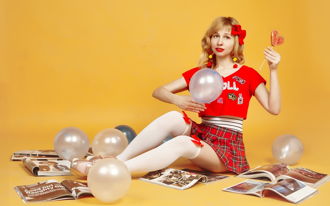 Девушка с шариками и журналами сидит на полу