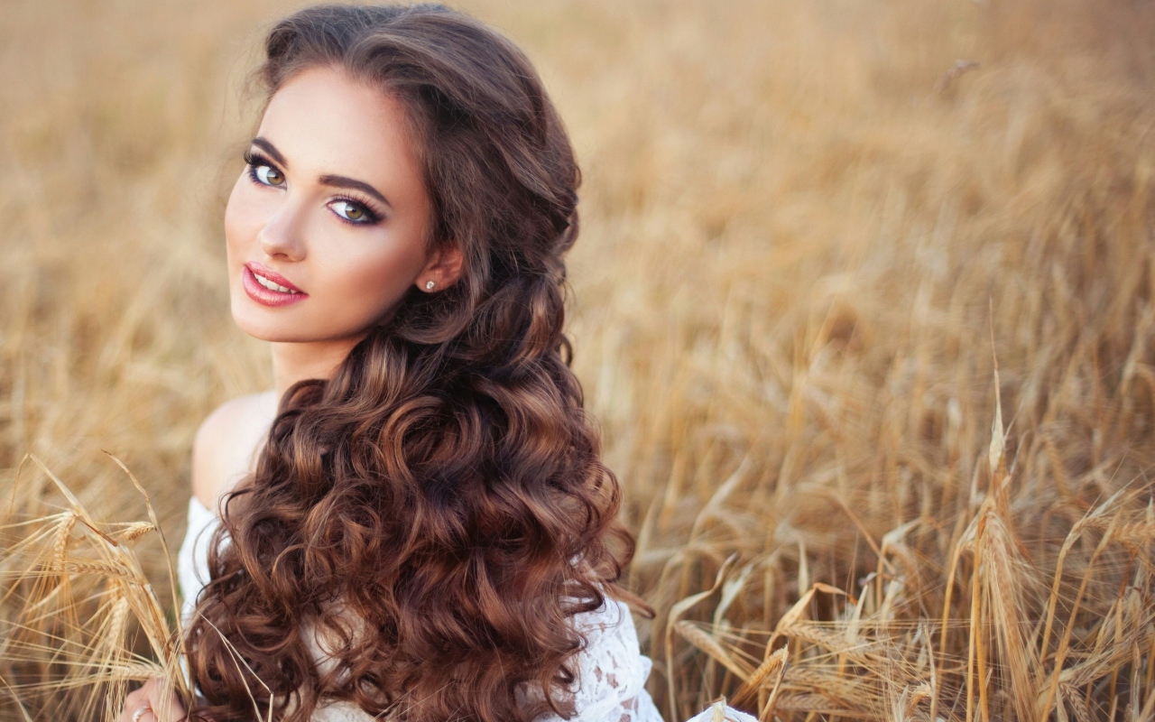 Девушка с красивыми длинными волосами на поле с пшеницей