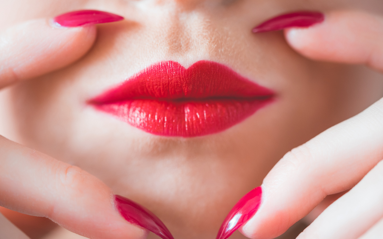 Руки с длинными красными ногтями у губ