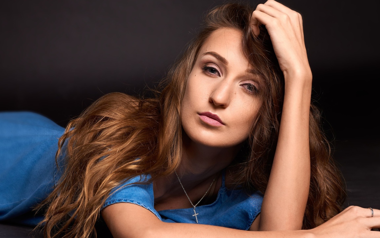 Длинноволосая шатенка лежит на полу в голубом платье 