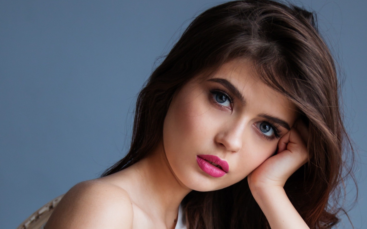 Милая девушка с розовыми губами на сером фоне