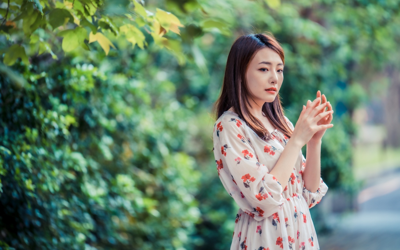 Грустная девушка азиатка в платье в парке