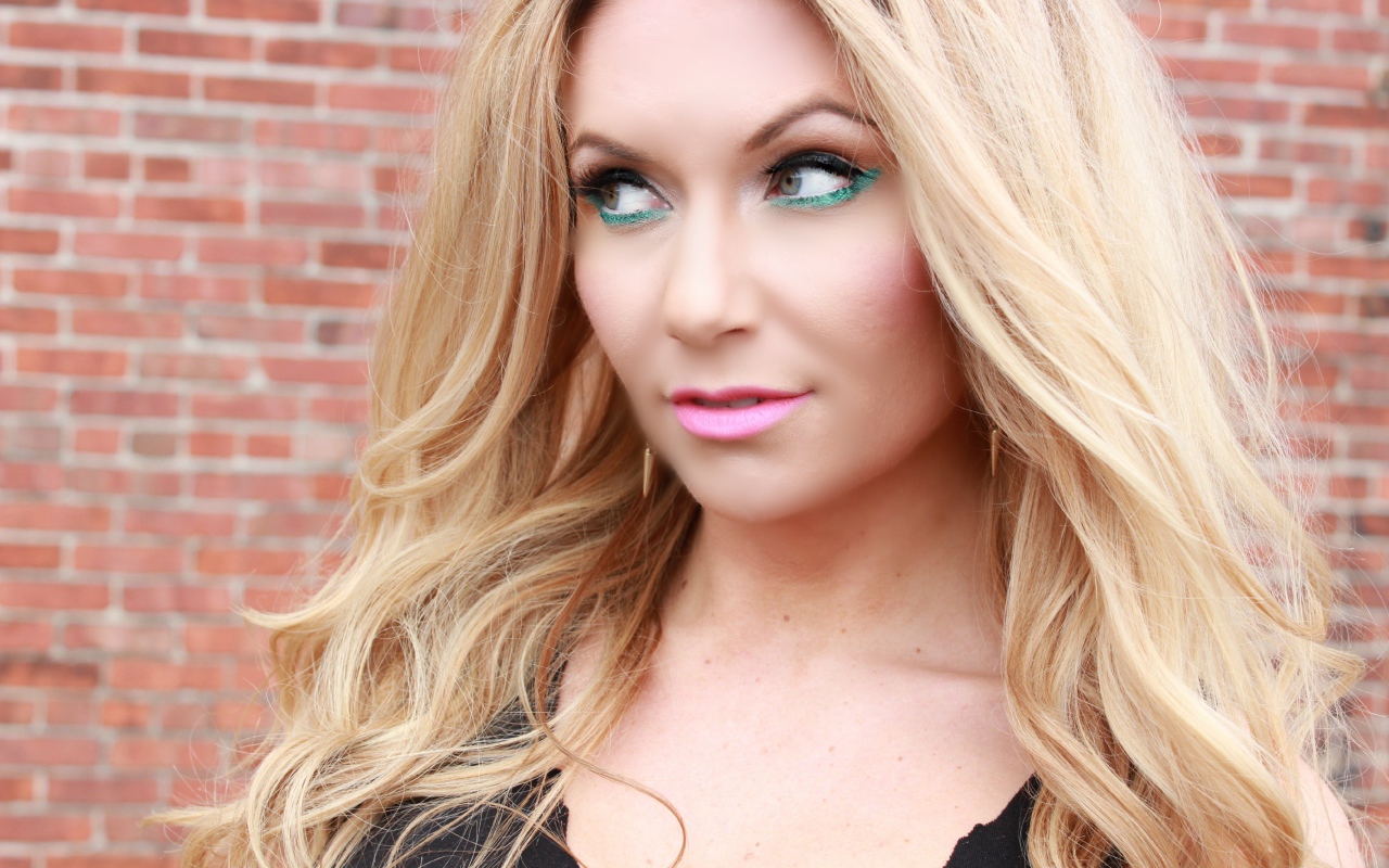 Эффектная длинноволосая блондинка у стены 