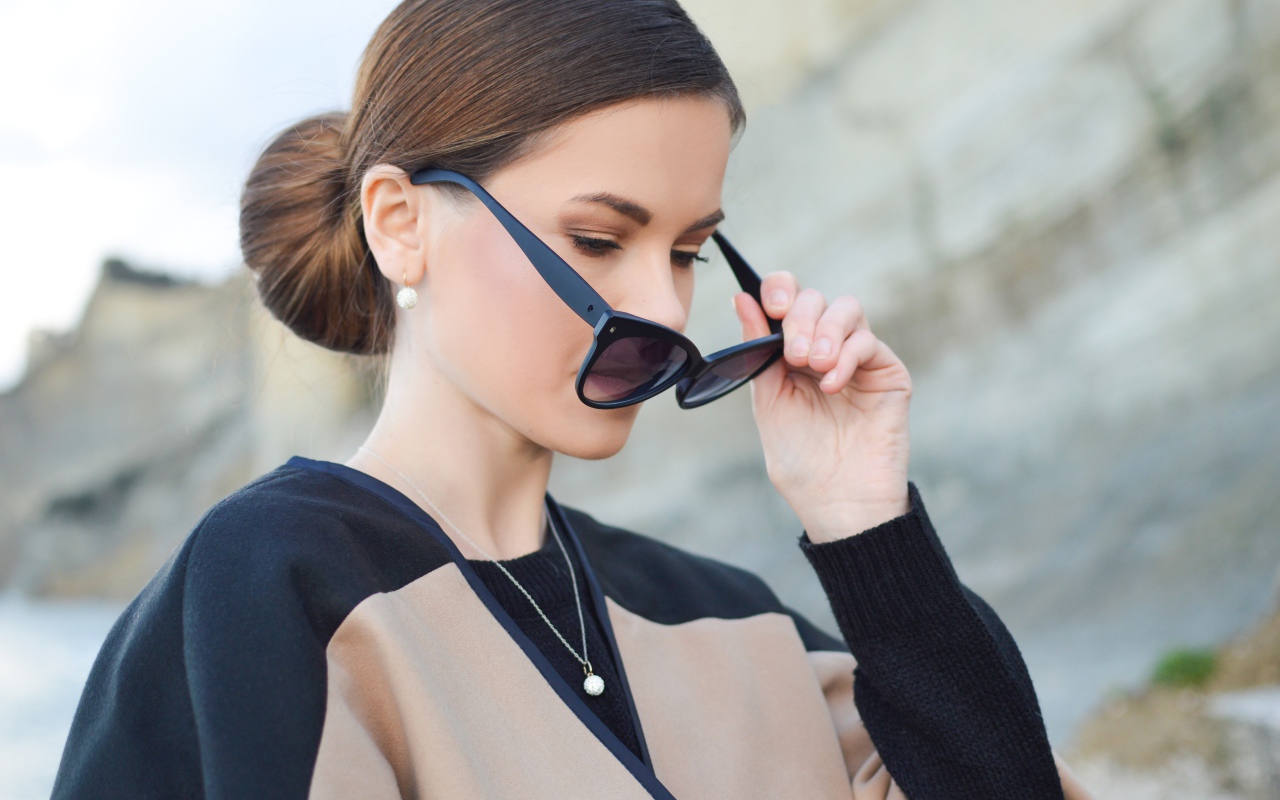 Стильная девушка с прической снимает очки