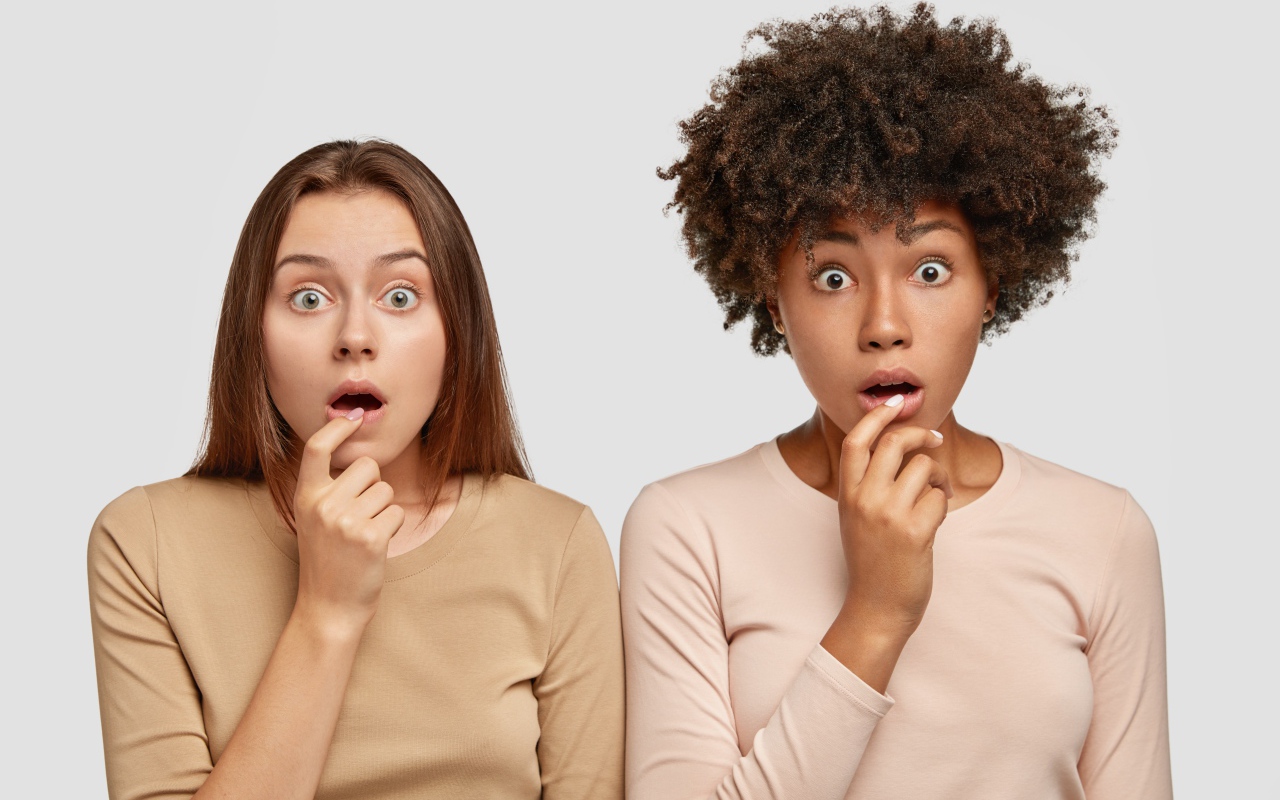Две удивленные девушки на сером фоне 