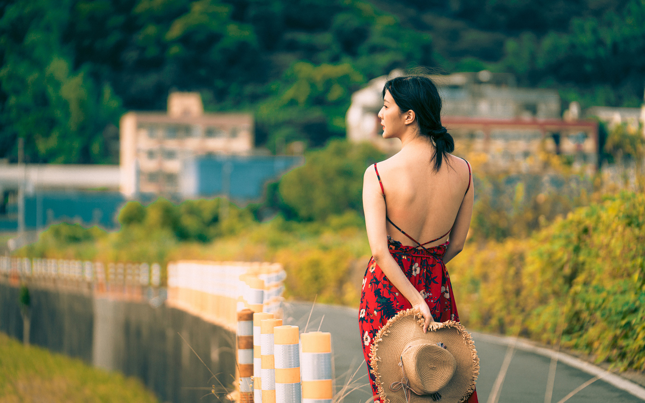 Молодая девушка азиатка в сарафане со шляпой в руке 