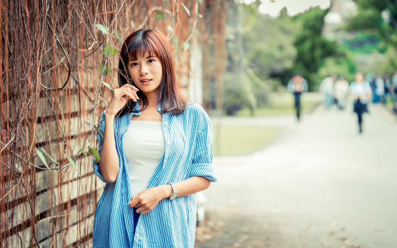 Молодая азиатка в рубашке у стены