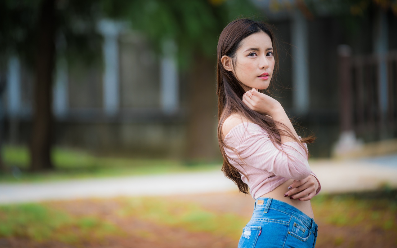 Молодая азиатка с длинными волосами в синих джинсах