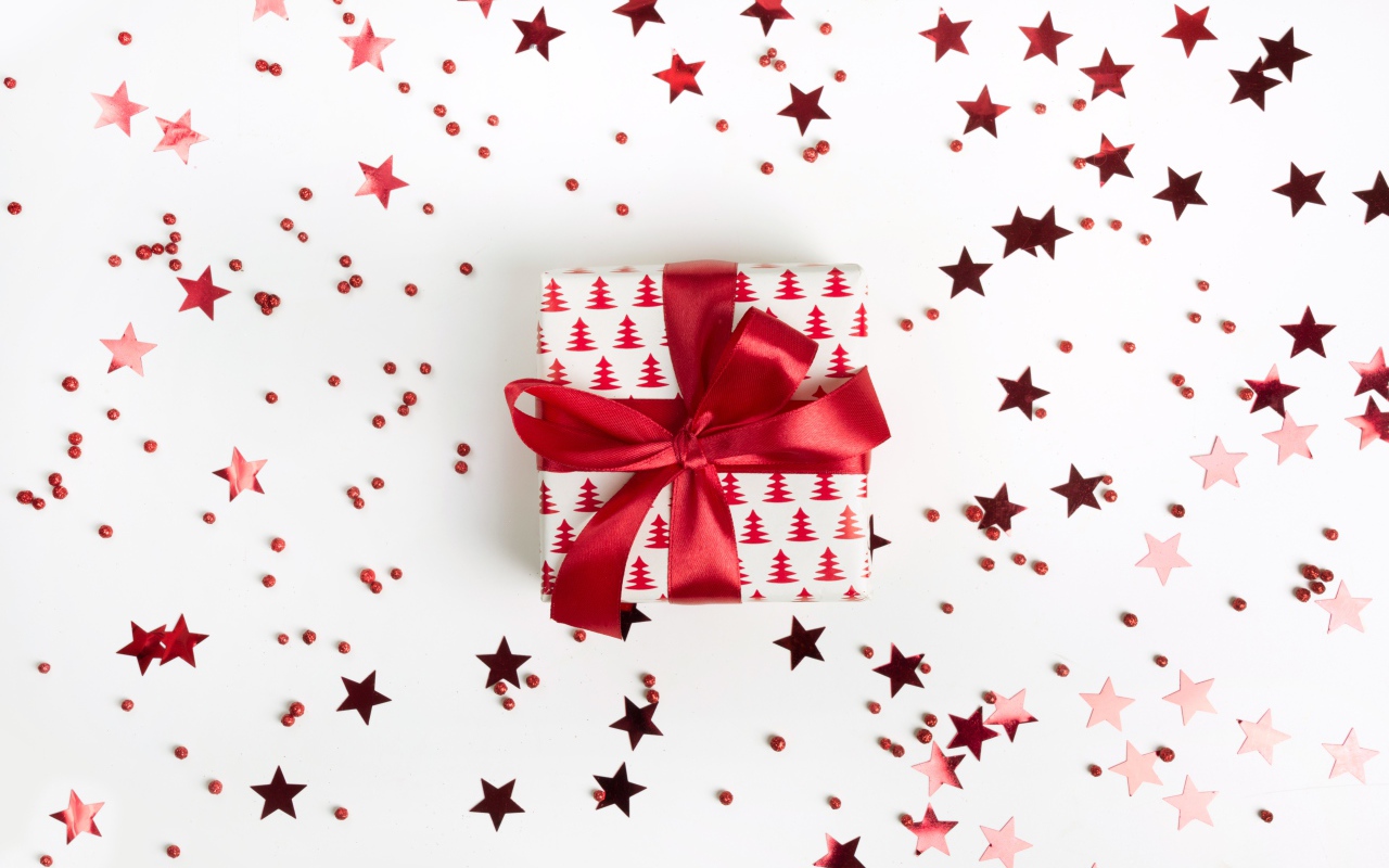 Подарок с красным бантом на белом фоне со звездочками