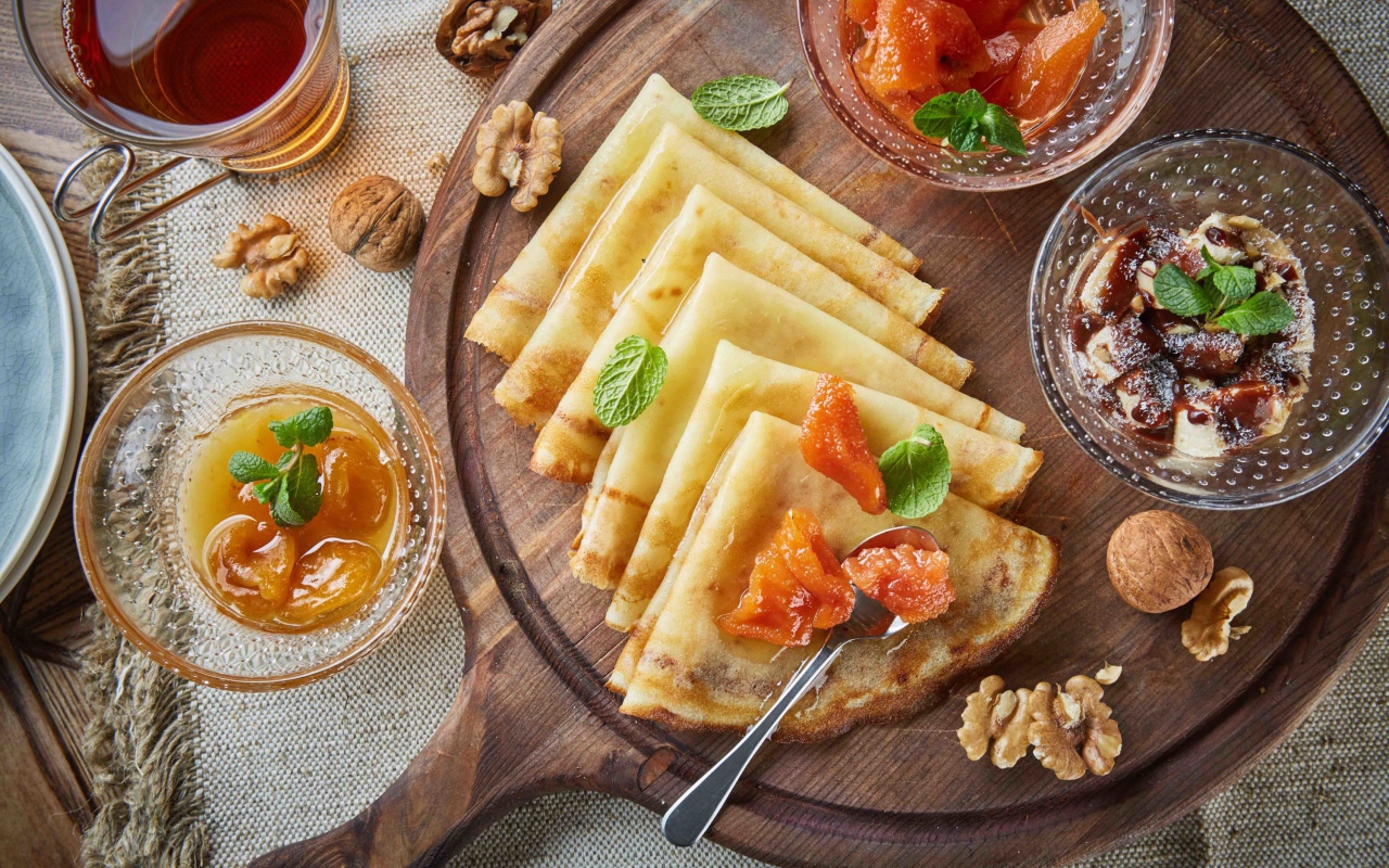 Тонкие блины с орехами и джемом на столе на Масленицу