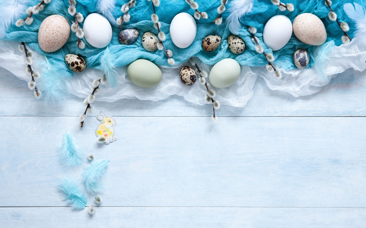 Яйца на ткани с ветками вербы на столе