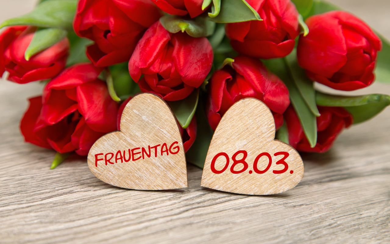 Два сердечка на столе с букетом красных тюльпанов на 8 марта 