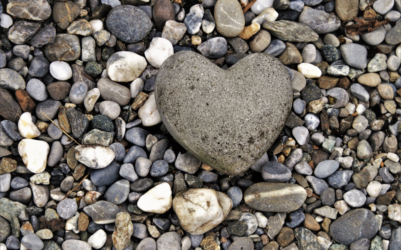 Большой камень в форме сердца лежит на морской гальке