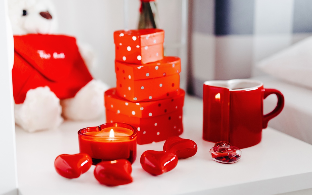 Чашка кофе на столе с подарками, зажженными свечами и сердечками