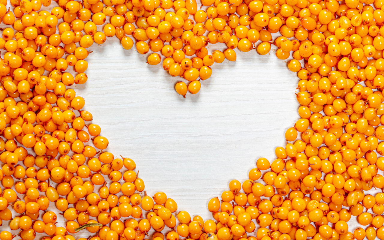 Сердце из ягод облепихи на столе 