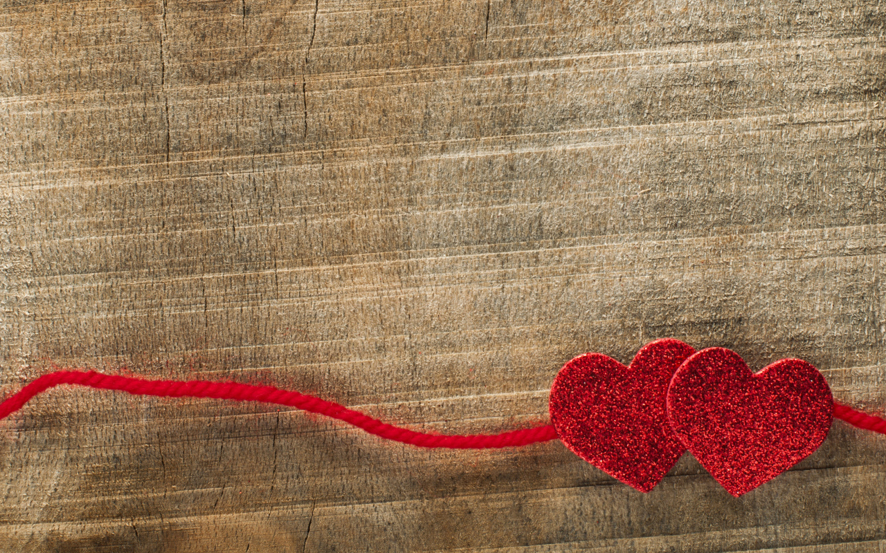 Два красных сердца со шнурком на деревянном фоне