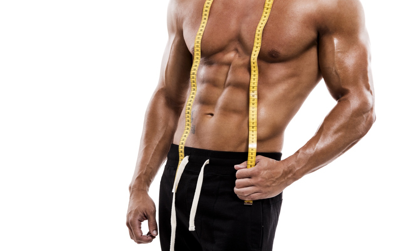 Накаченное тело спортивного мужчины с сантиметром на белом фоне