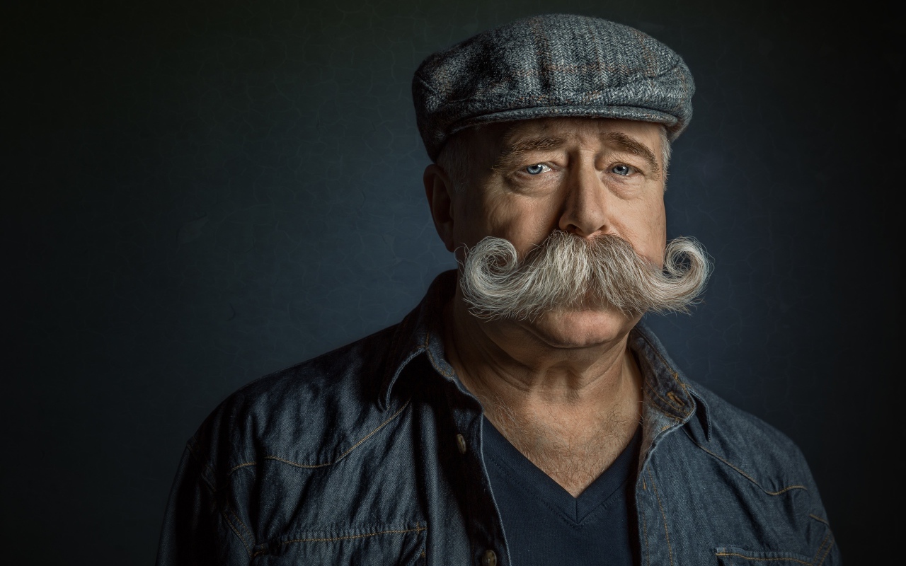 Мужчина в кепке с большими усами на лице 