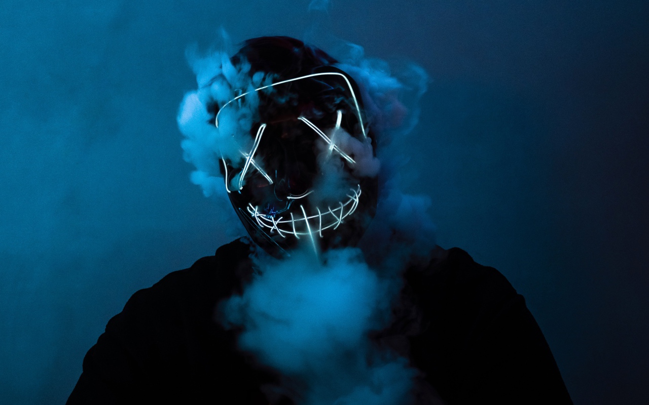 Smoke comes from under the neon mask of anonymous on the guy’s face